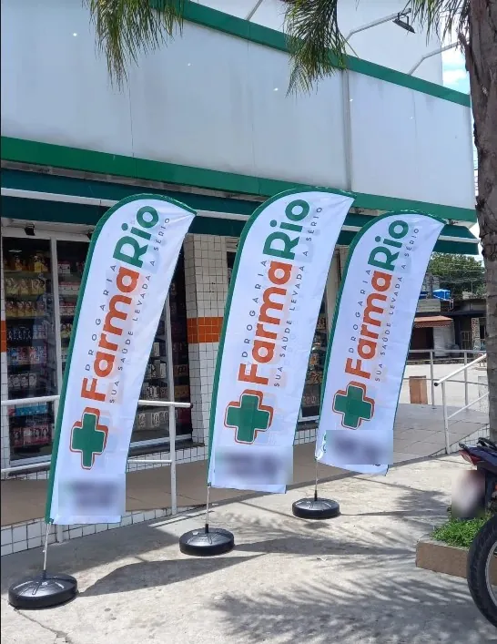 Três wind banners de drogaria na calçada